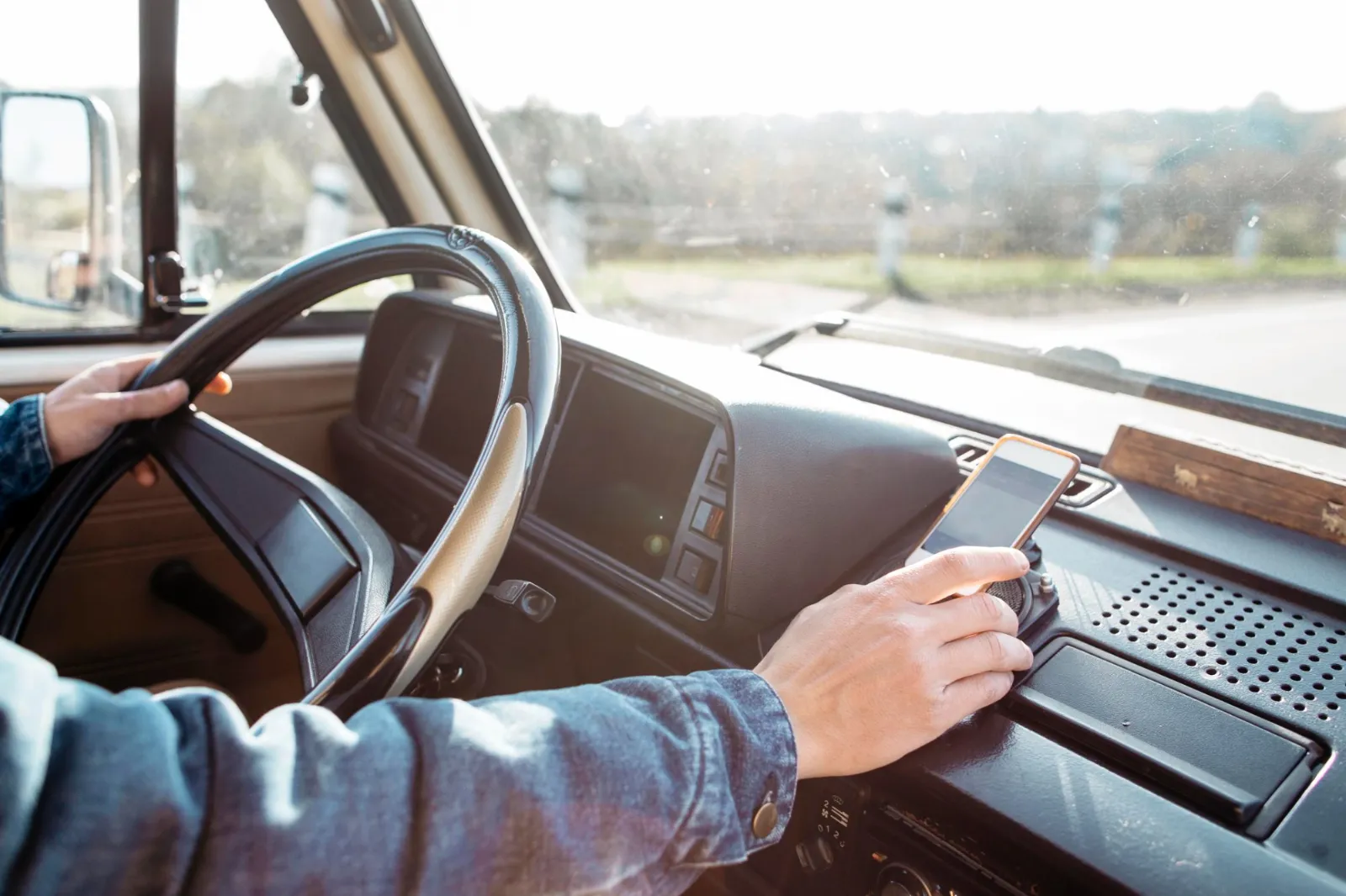 Motorista ao volante a usar o telemóvel no tablier